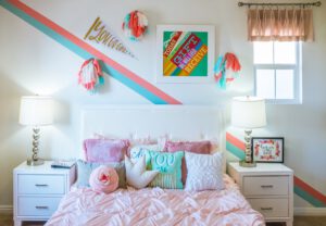 Child's bedroom with pink bedspread and brightly coloured wall decor